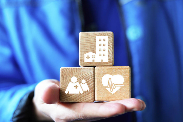 Молодой человек ручной укладки деревянных блоков с иконой медицинской помощи, страхование вашей концепции здоровья
 - Фото, изображение