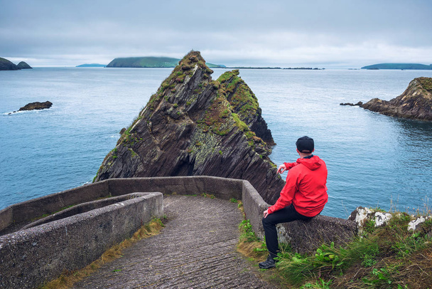 Turisti katselee jättimäisiä kallioita ja Irlannin saaria Dunquinin laiturilla, Dinglen niemimaalla, Irlannissa
 - Valokuva, kuva