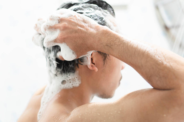 Primer plano joven lavando el cabello con champú en el baño, concepto de cuidado de la salud, enfoque selectivo
 - Foto, imagen