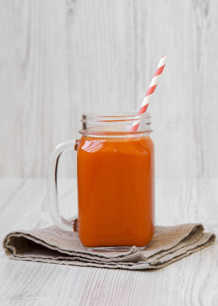 Mason glass jar mug filled with carrot smoothie on a white woode - Foto, afbeelding
