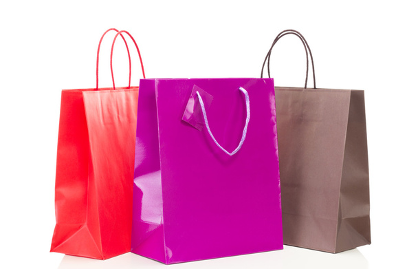 Beyaz masa üzerinde üç renkli alışveriş torbaları - Fotoğraf, Görsel