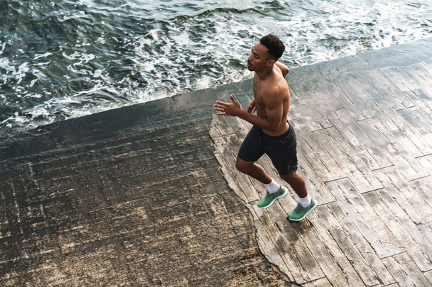 Молодой африканский спортсмен бегун на открытом воздухе на берегу моря бег делают упражнения
. - Фото, изображение