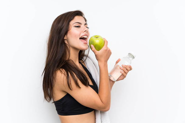 Ragazza sportiva adolescente su sfondo bianco isolato con una mela e una bottiglia d'acqua
 - Foto, immagini