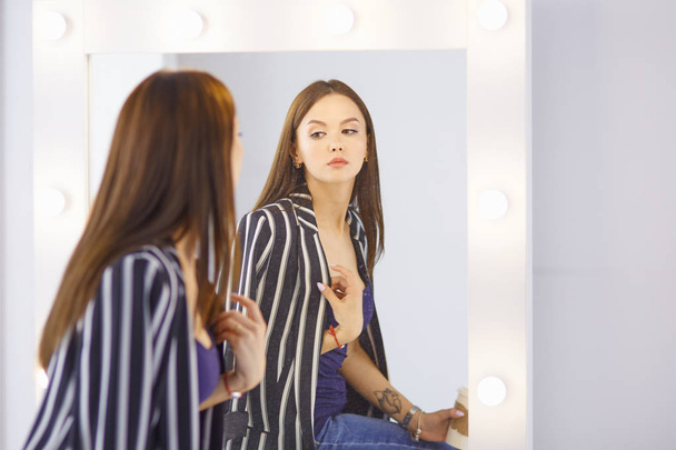 Дивовижна молода жінка робить макіяж перед дзеркалом. Портрет красивої дівчини біля косметичного столу
 - Фото, зображення