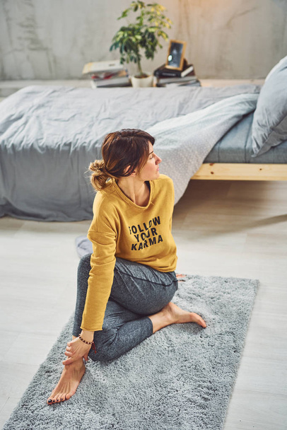 Приваблива кавказька брюнетка сидить на килимі в спальні в Maric - Фото, зображення