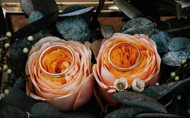 Dos anillos de boda en una caja dorada decorada con rosas y hojas. Cerrar imagen
. - Foto, Imagen