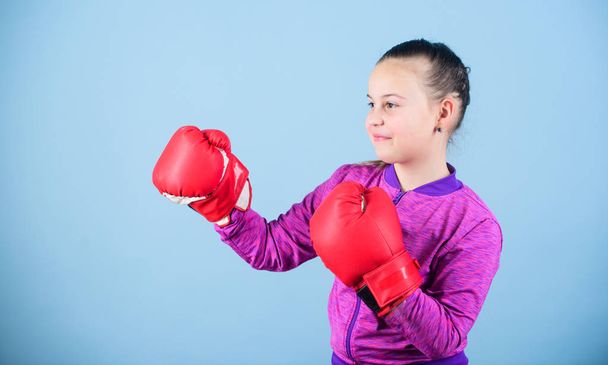 Contrary to stereotype. Boxer child in boxing gloves. Confident teen. Enjoyment from sport. Female boxer. Sport upbringing. Boxing provide strict discipline. Girl cute boxer on blue background - Фото, изображение