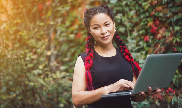 Mulher de negócios asiática bonita posando com laptop ao ar livre
 - Foto, Imagem