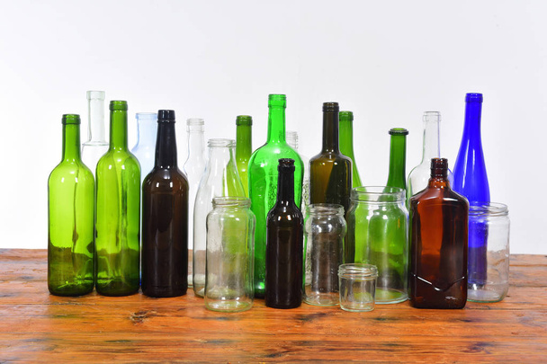 grupo de garrafas e frascos de vidro em uma mesa de madeira com bac branco
 - Foto, Imagem