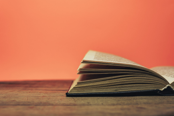 Open book on a  old wooden round table. beautiful coral orange background. - Foto, Bild