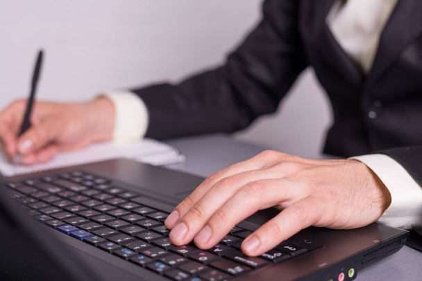Businessman write in paper documents over the laptop keyboards. - Zdjęcie, obraz