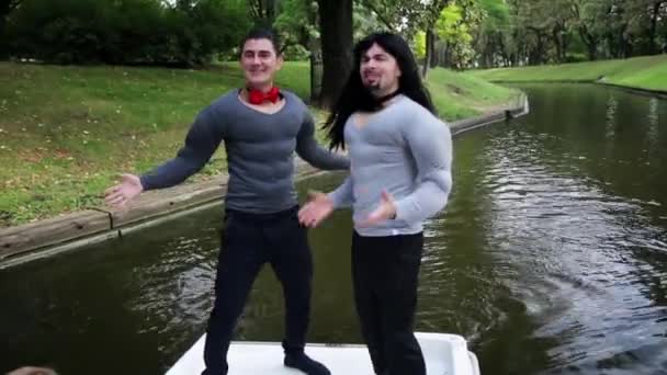 Twee goed uitziende grappige mannen gekleed in nep spier kostuums zingen in boot - Video