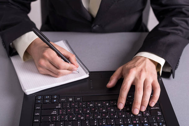 Empresario escribir en documentos en papel sobre los teclados del ordenador portátil
. - Foto, imagen
