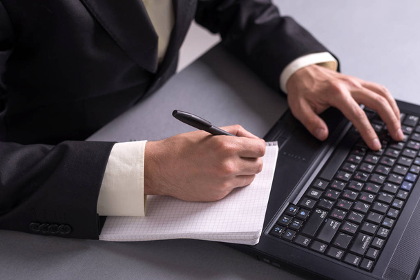 Businessman write in paper documents over the laptop keyboards. - Фото, зображення