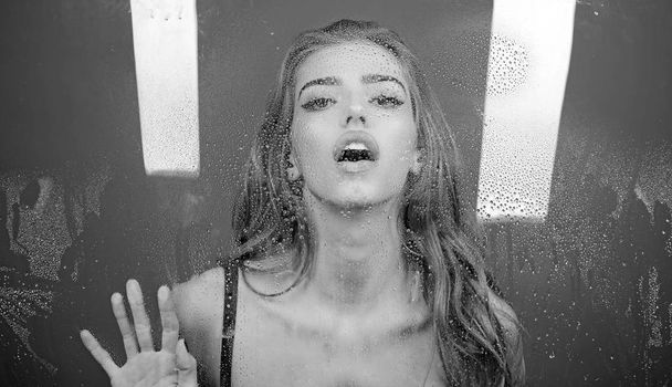 Sexy woman behind plastic sheet with water drops. Shower and hygiene spa treatment. Window with water drops before girl with makeup. Rain drops on window glass with face of girl. Fashion and beauty - Photo, Image