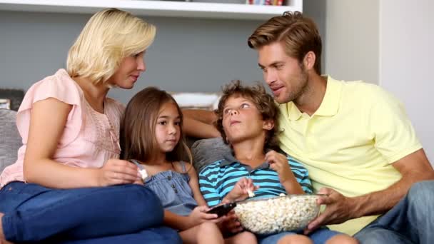 Family eating popcorn and watching tv together - Materiał filmowy, wideo