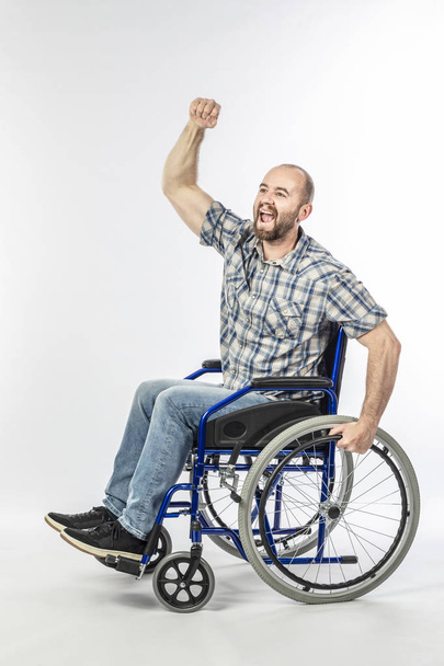 Disabled man on wheelchair with arm raised  - Фото, изображение