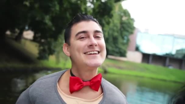 Przystojny facet w fałszywej koszuli mięśni i łuk tie tańce i śpiewa w pływającej łodzi - Materiał filmowy, wideo