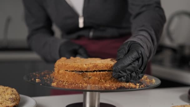 Female pastry chef slicing cake standing on rotary bar. Chef cuts cakes. Juicy cakes for delicious cake. Woman hand in black gloves cutting sponge-cake. - Séquence, vidéo