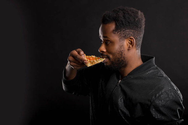 Close up portrait of young african man eating pizza - Fotó, kép