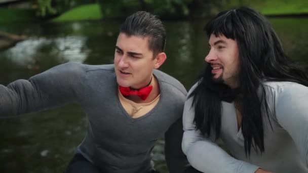 Srandovní muži v napodobeniny svalových kostýmů tančí a zpívají na plovoucím voru - Záběry, video