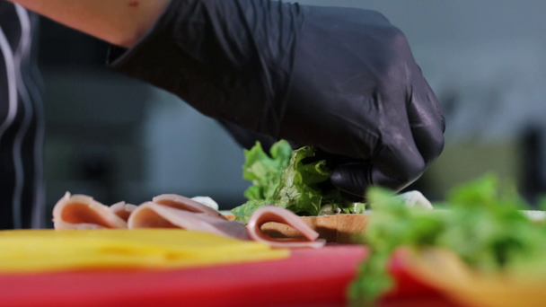 Man puts lettuce on bread while cooking sandwich. - Séquence, vidéo