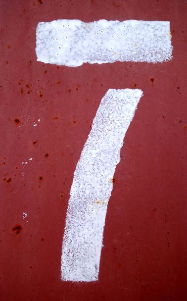 Nummer 7 in stencil op rode metalen wand. - Foto, afbeelding