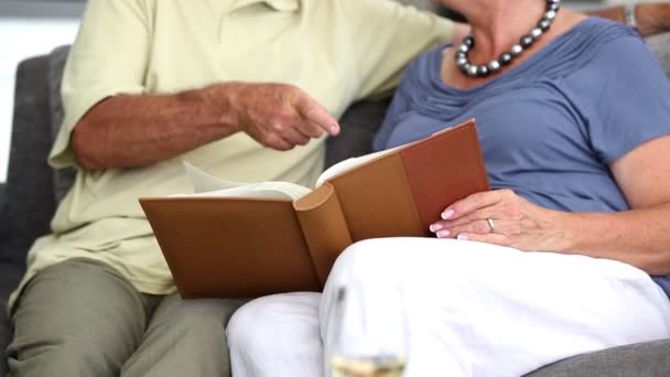 Mature couple laughing while looking at a book - Záběry, video