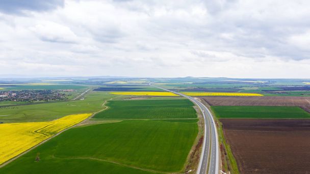 Moving cars on a fast road between rape fields. - Photo, Image
