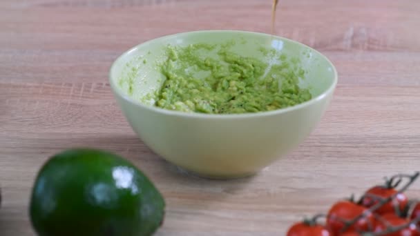 Kuchař nalije olivový olej do mísy guacamolu. Koncepce zdravého jídla. - Záběry, video
