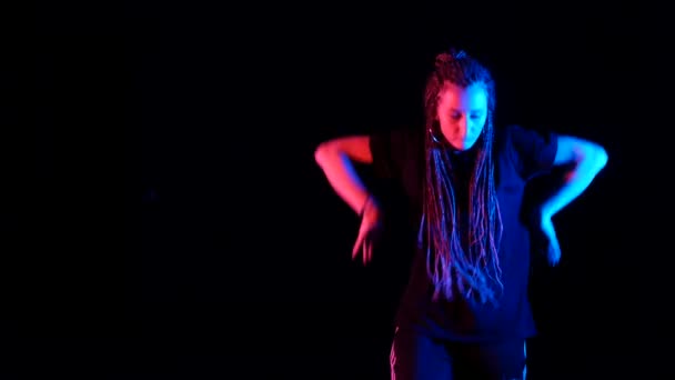 Afrika örgülü güzel bir kız hip hop yapıyor, stüdyoda siyah bir arka planda sokak dansı yapıyor, izole edilmiş. - Video, Çekim