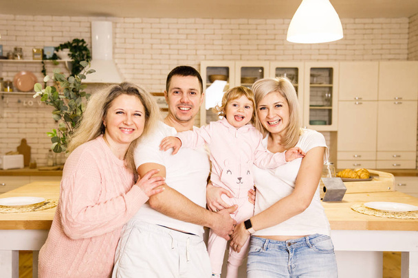 beautiful family dad mom and daughter have fun in the kitchen in a bright apartment - Photo, image