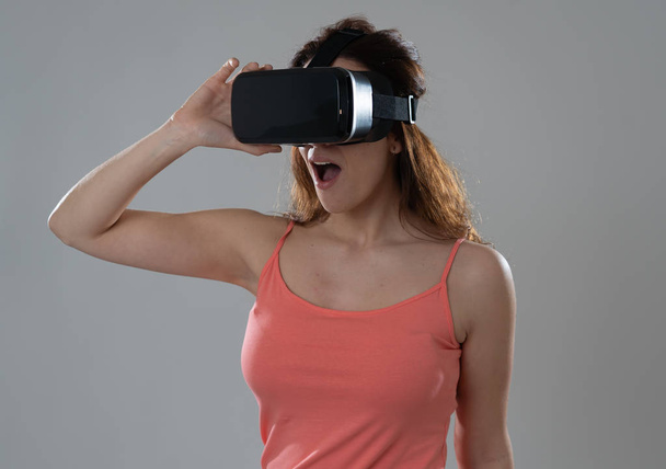 Curious woman happy and excited to use virtual reality goggles feeling excited about simulation, exploring virtual life making happy gestures. In New technology Virtual Augmented Reality concept. - Foto, imagen