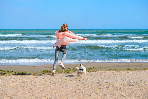 Happy young girl run with dog on beach. - Foto, imagen