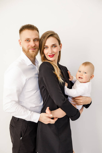 young beautiful family stylishly dressed standing in a bright apartment - 写真・画像