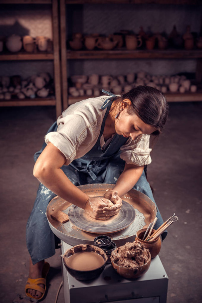 Encantadora alumna alfarera muestra cómo trabajar con arcilla y rueda de cerámica. Trabajos manuales
. - Foto, imagen