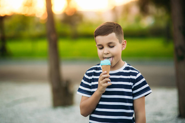 Malého chlapce v pruhovaném tričku je jíst zmrzlinu modrá. Jaro, slunečné počasí - Fotografie, Obrázek