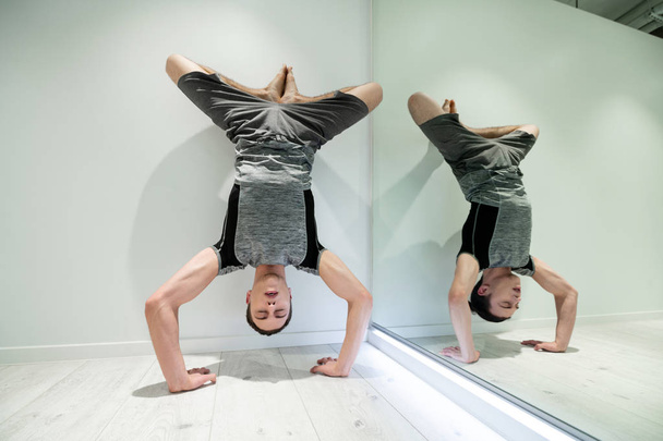 Man loving sport closing eyes while doing arm stand after yoga - Photo, image