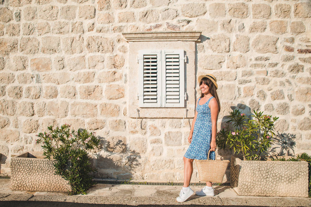woman posing in front of stone wall with wooden window with shutter - Φωτογραφία, εικόνα