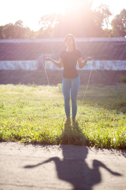 Slender woman athlete in sport apparel doing workout with jump r - Fotó, kép
