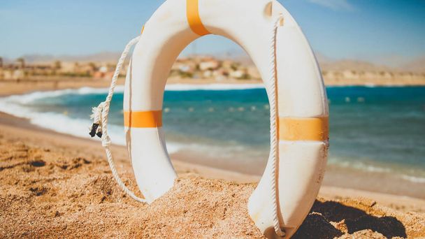 Пейзаж песчаного морского пляжа и белое пластиковое спасательное кольцо. Перфект, снятый для иллюстрации летнего отпуска в океане
. - Фото, изображение