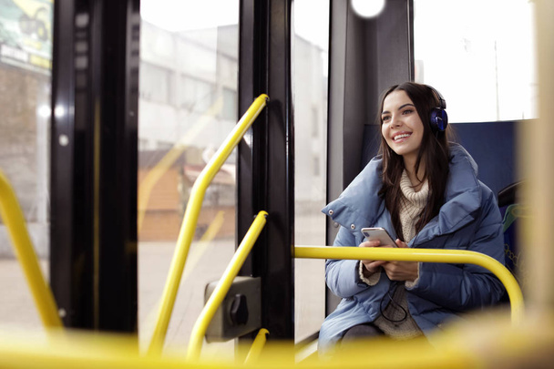 Mujer joven escuchando música con auriculares en el transporte público
 - Foto, imagen