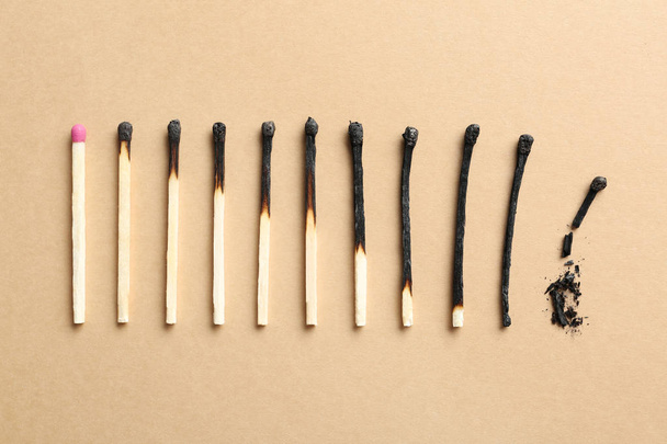 Row of burnt matches and whole one on color background, flat lay. Human life phases concept - Фото, зображення