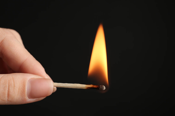 Woman holding burning match on black background, closeup. Space for text - Foto, Bild