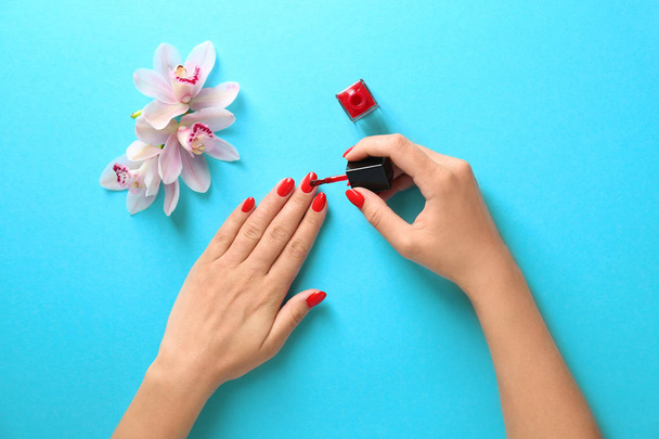 Woman applying bright nail polish on color background, top view - Foto, Imagen