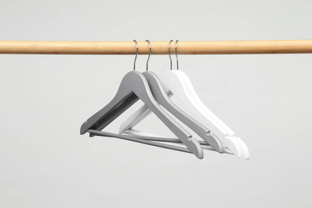 Empty clothes hangers on wooden rail against light background - Foto, Imagem