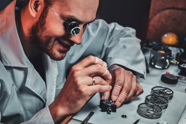 Routinierter Uhrmacher repariert alte Uhr für einen Kunden in seiner Werkstatt - Foto, Bild