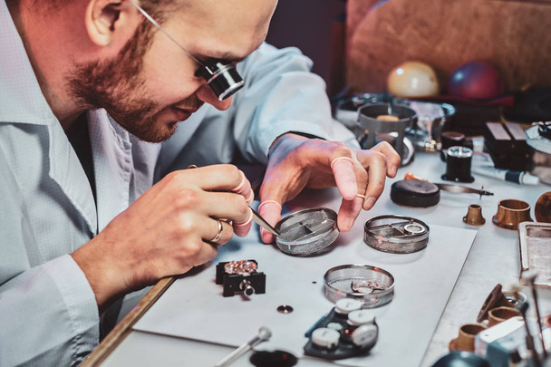 Expirienced clockmaster is fixing old watch for a customer at his repairing workshop - Foto, Imagem