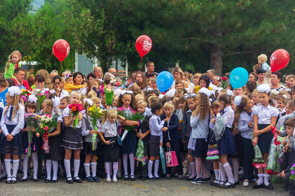 Adygea, Russia - September 1, 2018: children enrolled in the first class with bouquets of flowers and balloons in the hands, teachers and high school students on the school solemn parade - Foto, afbeelding