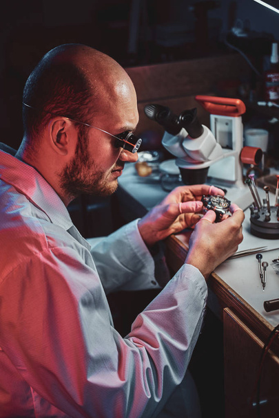 Serious watchmaker  is repairing cutomers order at his own repairing studio - Photo, Image